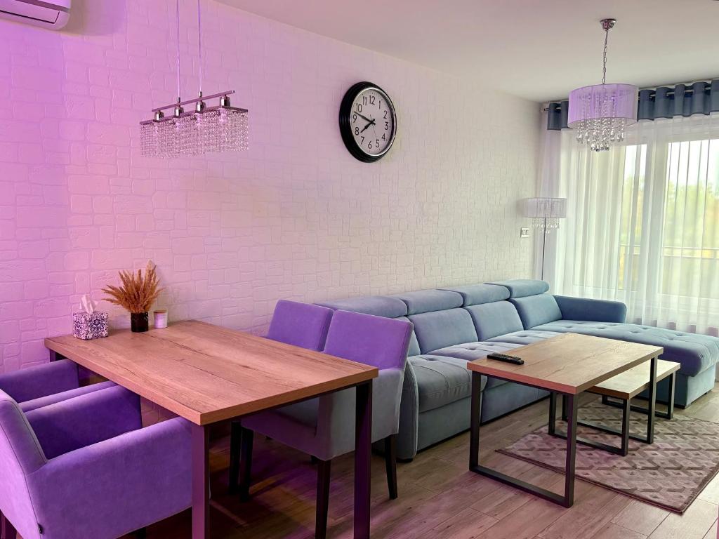 ein Wohnzimmer mit einem blauen Sofa und lila Stühlen in der Unterkunft ApartamentywInie in Inowrocław