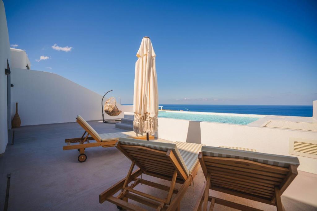 un patio avec deux chaises et un parasol dans l'établissement Villa Deep Blue Modern Seaview Villa with Infinity Pool near Lido Beach, à Orga