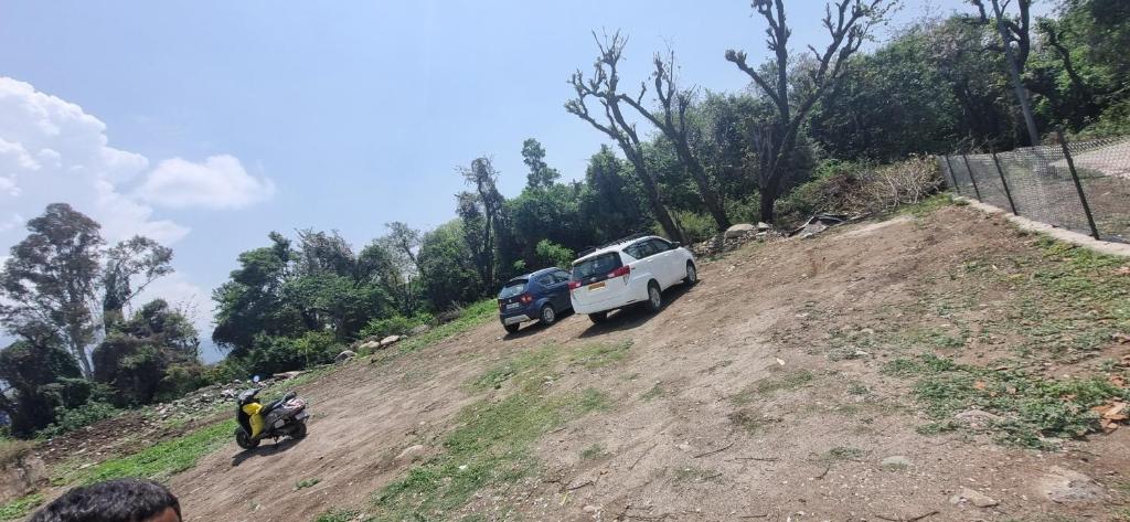 a white truck parked on a dirt hill with two people at Peace Yard in Dharmsāla