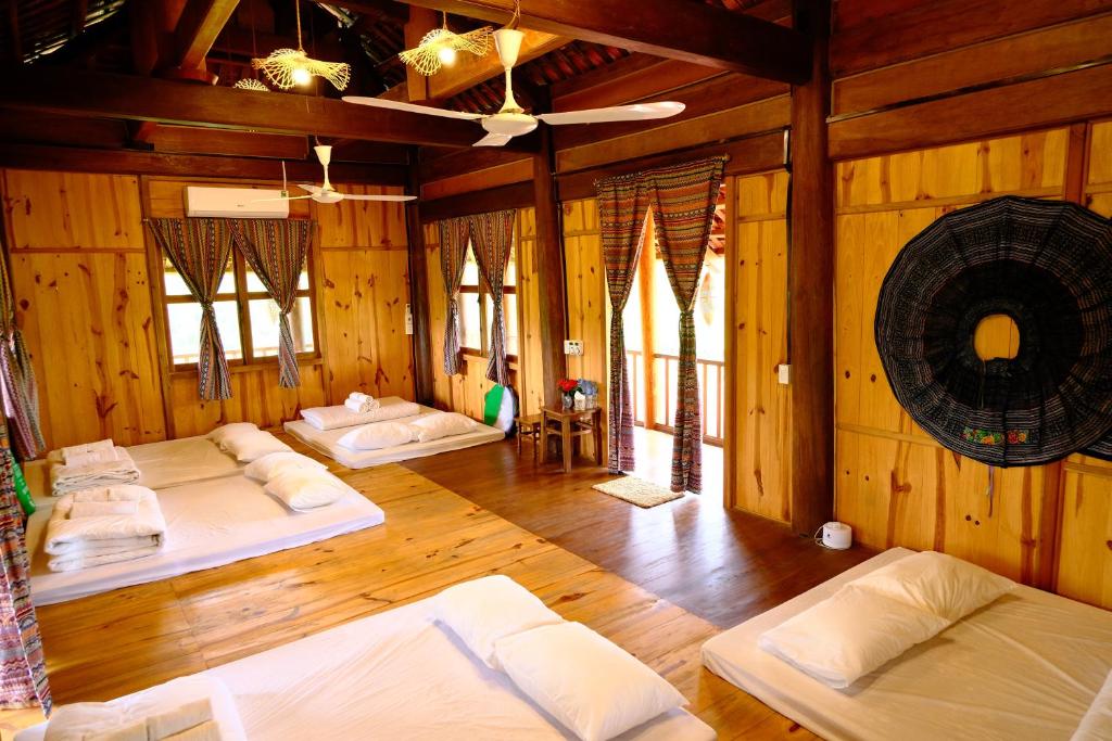 a room with four beds in a room with wooden walls at Nhà sàn cộng dồng - The Valley Farm in Hữu Lũng