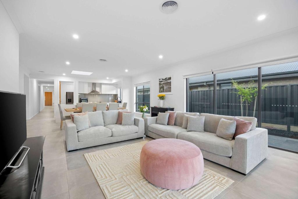 a living room with two couches and a pink stool at Hathaway Haven in Alfredton
