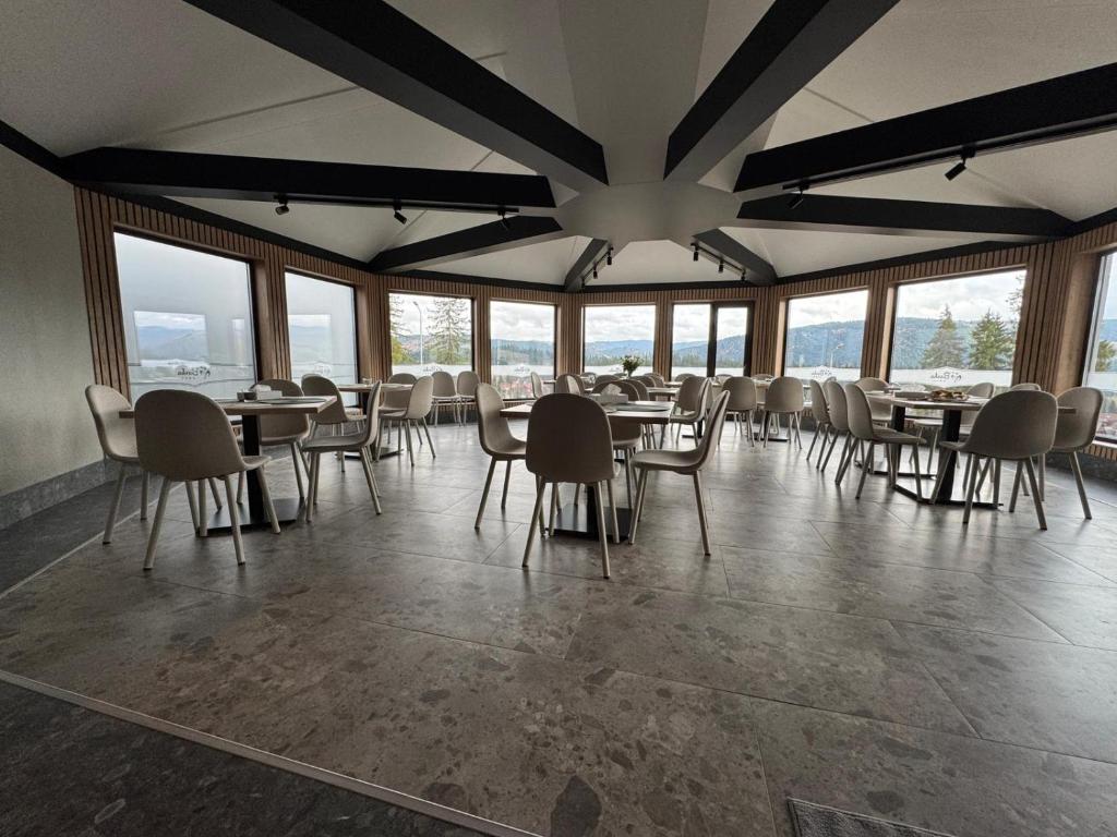 Un comedor con mesas y sillas y ventanas. en Barka, en Borsec
