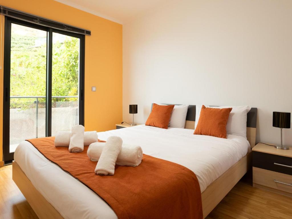 a bedroom with a large bed with orange walls at Skyline Villas Top in Arco da Calheta