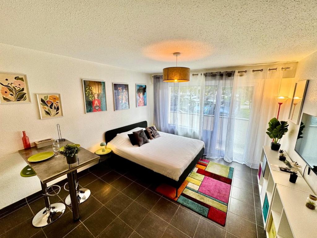 Un dormitorio con una cama, una mesa y un televisor. en Appartement Frontalier 1, en Saint-Julien-en-Genevois