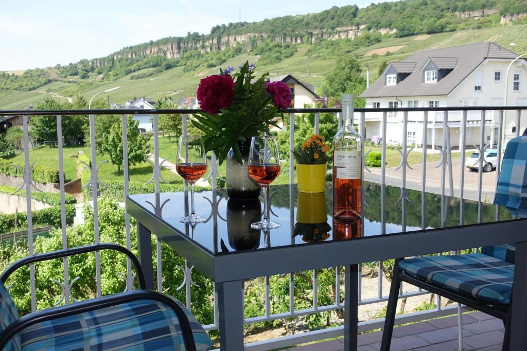 a table with wine glasses and flowers on a balcony at Weingut Pension Heinz Dostert in Nittel