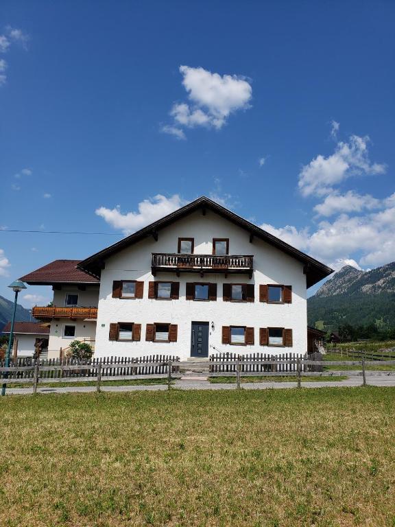 a white building with a fence in front of a field at Rosa s Ferienhaus in Grän