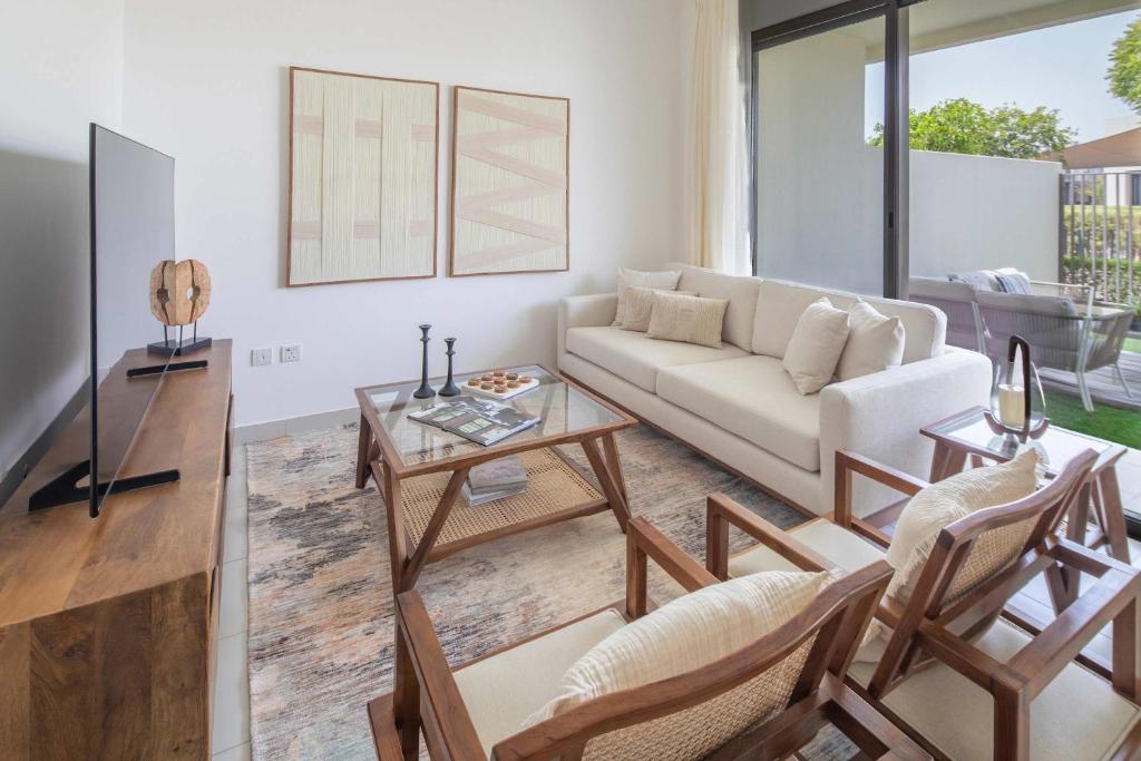 a living room with a couch and a table at Frank Porter - Parkside 2, Emaar South in Ghantoot