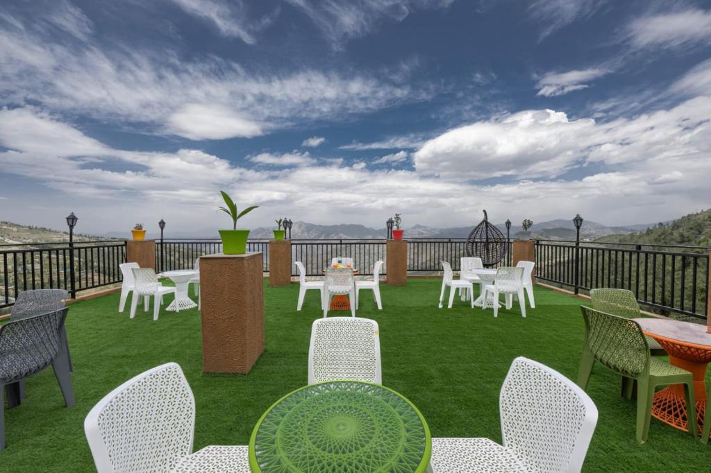 a patio with white chairs and tables on the grass at The Charvi Retreat by Exotic Stays in Shimla