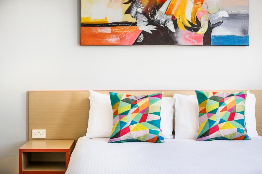 1 cama con 2 almohadas y una pintura en la pared en Granville Hotel en Sídney