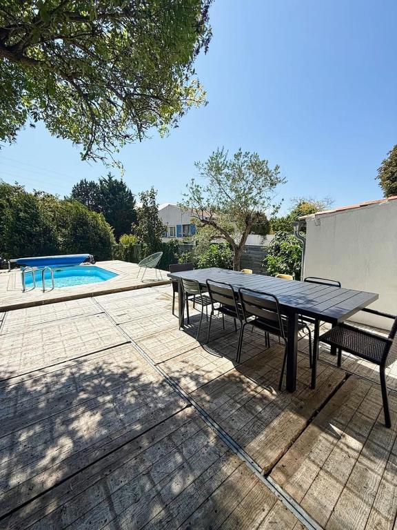 a picnic table and chairs next to a swimming pool at L'échappée, piscine, billard et parking privé in Lagord
