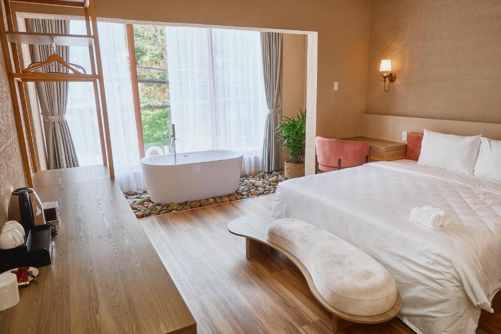 Un dormitorio con una cama grande y una bañera. en Enjoy Hotel Đà Lạt, en Da Lat