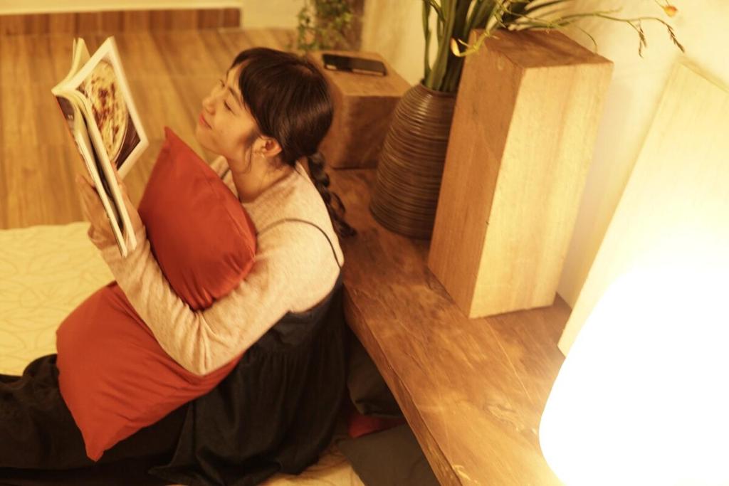 a man sitting on the floor holding a pillow at Brownie Home Dalat in Da Lat
