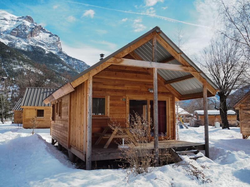 a log cabin in the snow with a mountain at Huttopia Vallouise in Vallouise