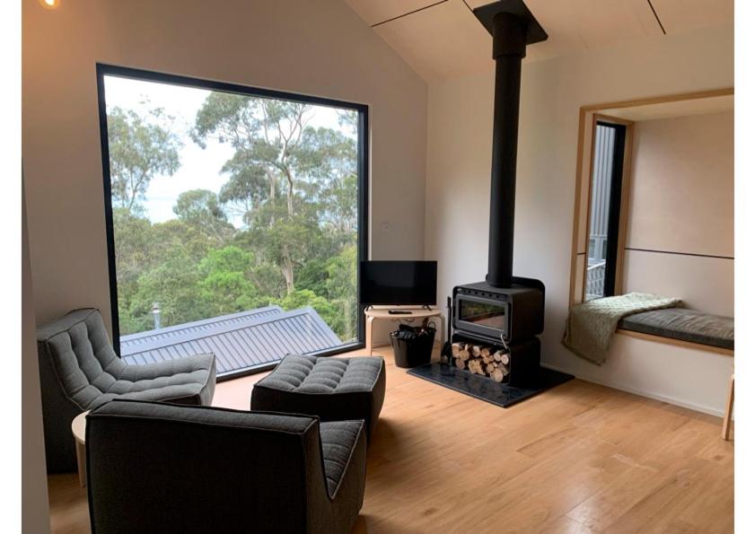 a living room with a fireplace and a couch and a stove at Perch Lorne in Lorne