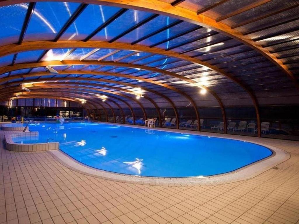 a large indoor swimming pool with a curved ceiling at Les Ch'tis Normands 2! in Litteau