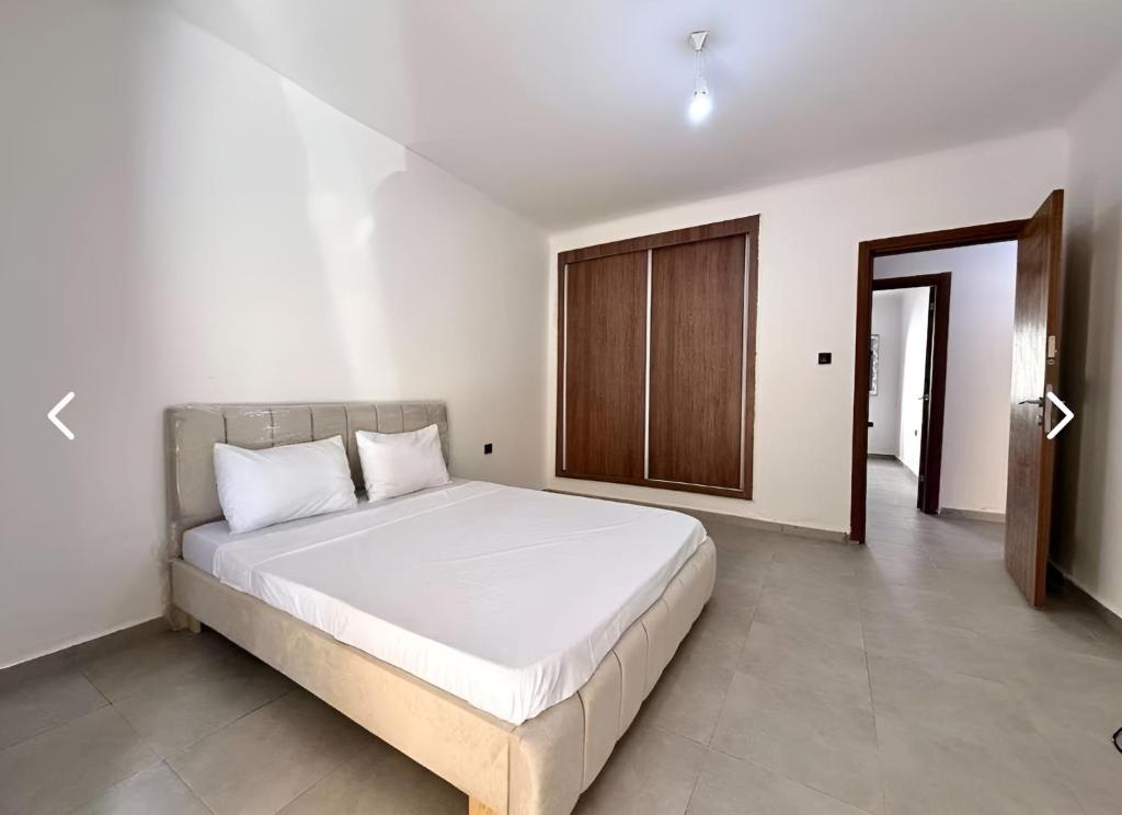 a bedroom with a large white bed and a wooden door at Charming apartment in Oran in Bir el Djir