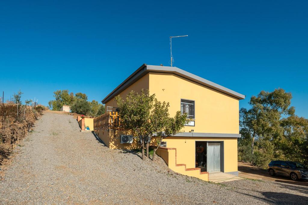 a yellow house on the side of a gravel road at Affittacamere Gutturu e Forru in Villacidro