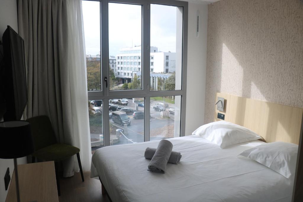 Ce lit se trouve dans une chambre d'hôtel dotée d'une grande fenêtre. dans l'établissement Abalys Hotel, à Brest