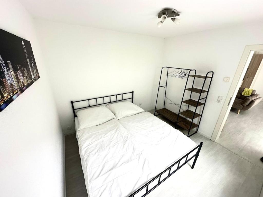 a bedroom with a bed with white sheets and a shelf at Schwarzwald - Modern mit Terrasse in Schramberg