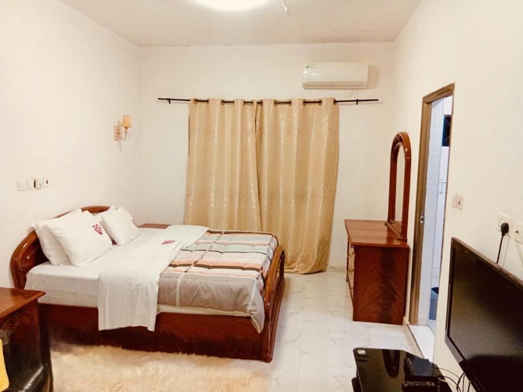 a bedroom with a bed and a television in it at Odo So Royal Hotel in Oko Sombo