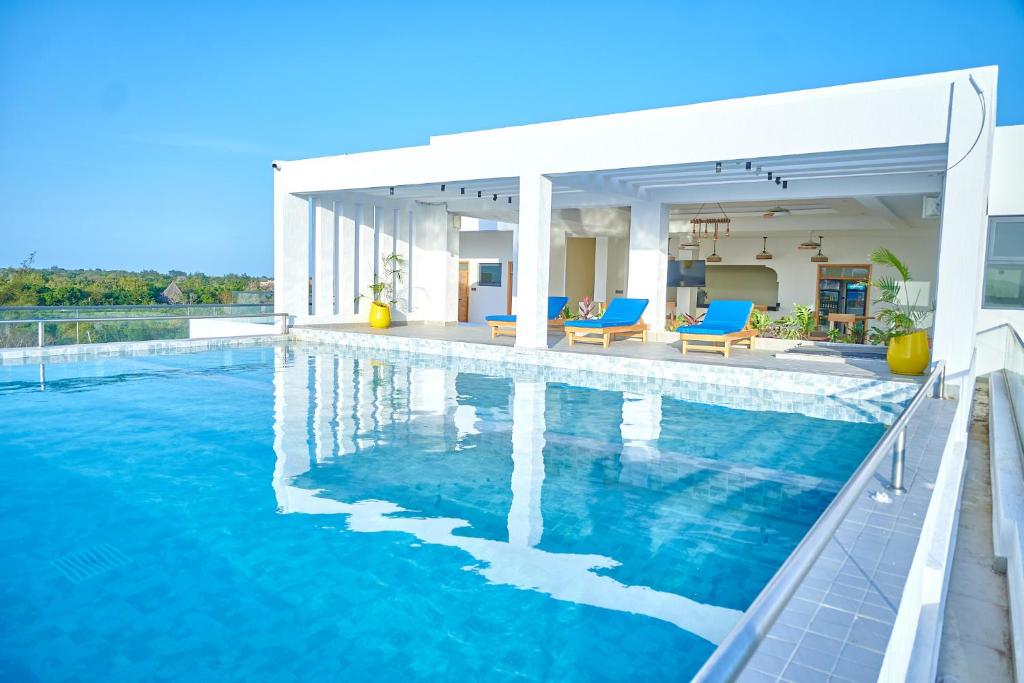 a swimming pool with blue chairs and a house at Marikeka Hotel in Galu