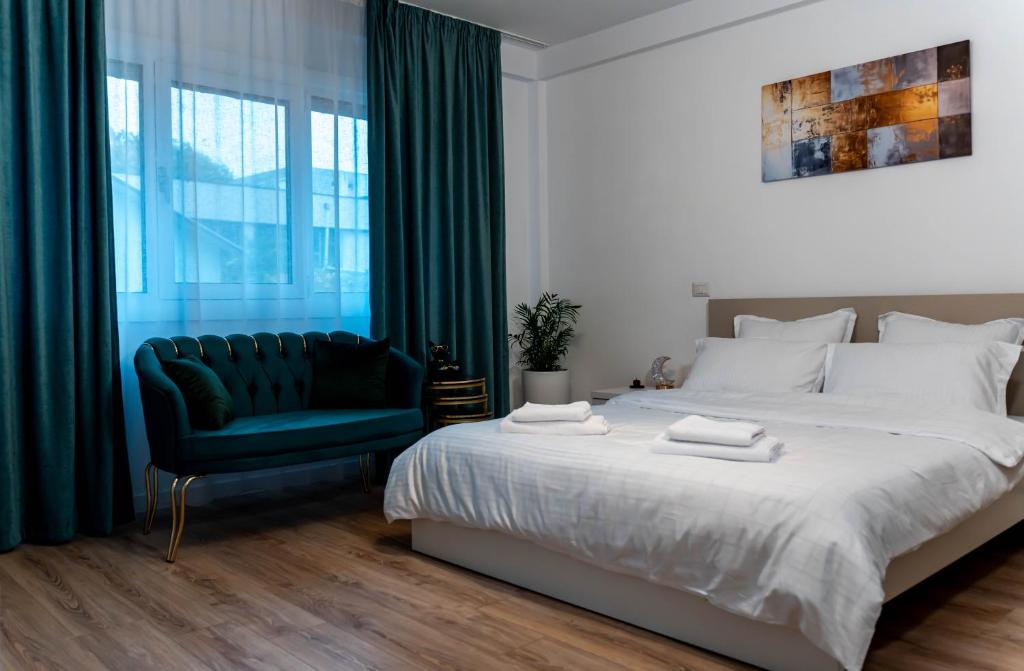 a bedroom with a large bed and a green chair at Vanguard Suite De Lux in Craiova