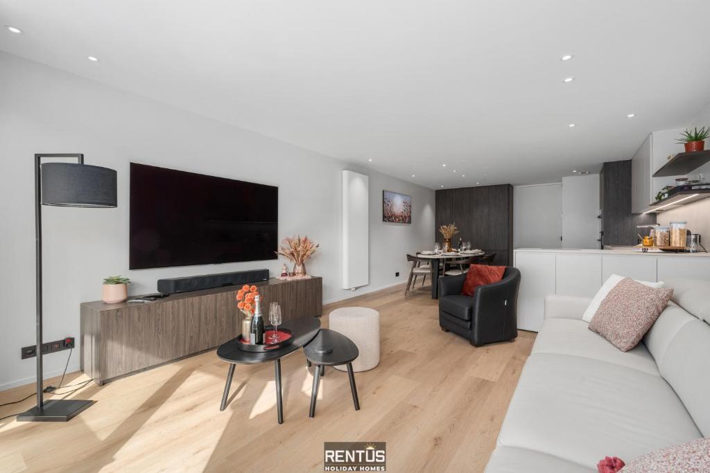 een woonkamer met een witte bank en een tv bij Newport 3 - luxury apartment with side sea view in Nieuwpoort
