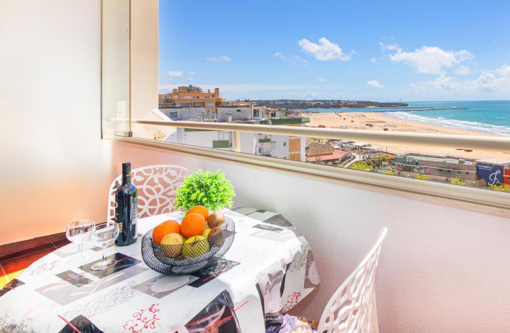 a table with a bowl of fruit and a view of the beach at Varandas da Rocha - Silhueta Citadina in Portimão