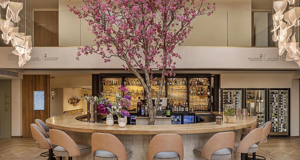 a lobby with a bar with chairs and flowers at Best Western Plus Hotel Saint-Roch Orleans in Orléans