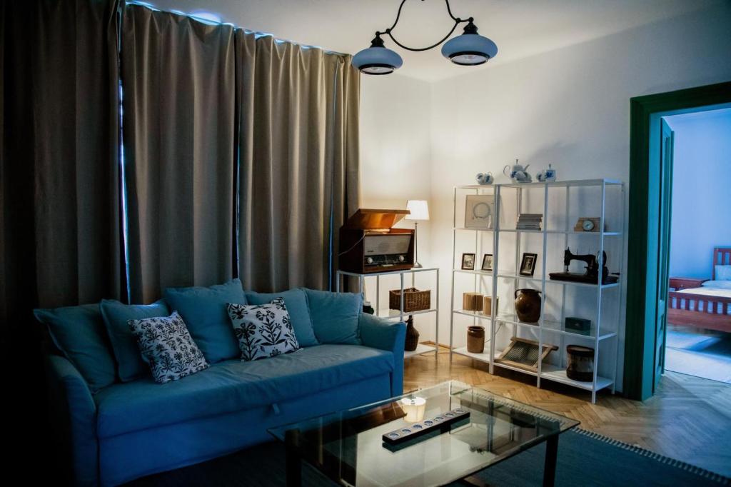 a living room with a blue couch and a glass table at Nostalgia in Turda