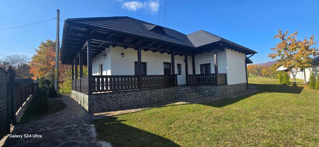 a small white house with a black roof at Casa LEO in Filioara