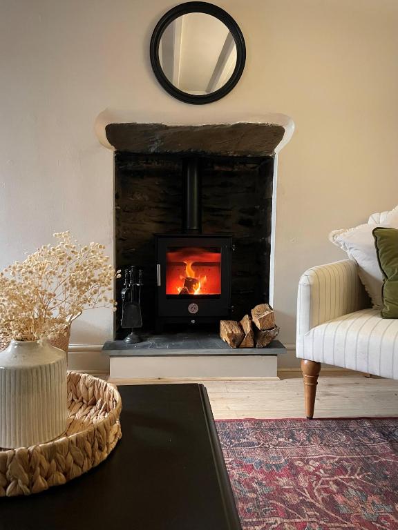 a living room with a fireplace and a couch at Poets Cottage Eglwys Fach in Scyborycoed