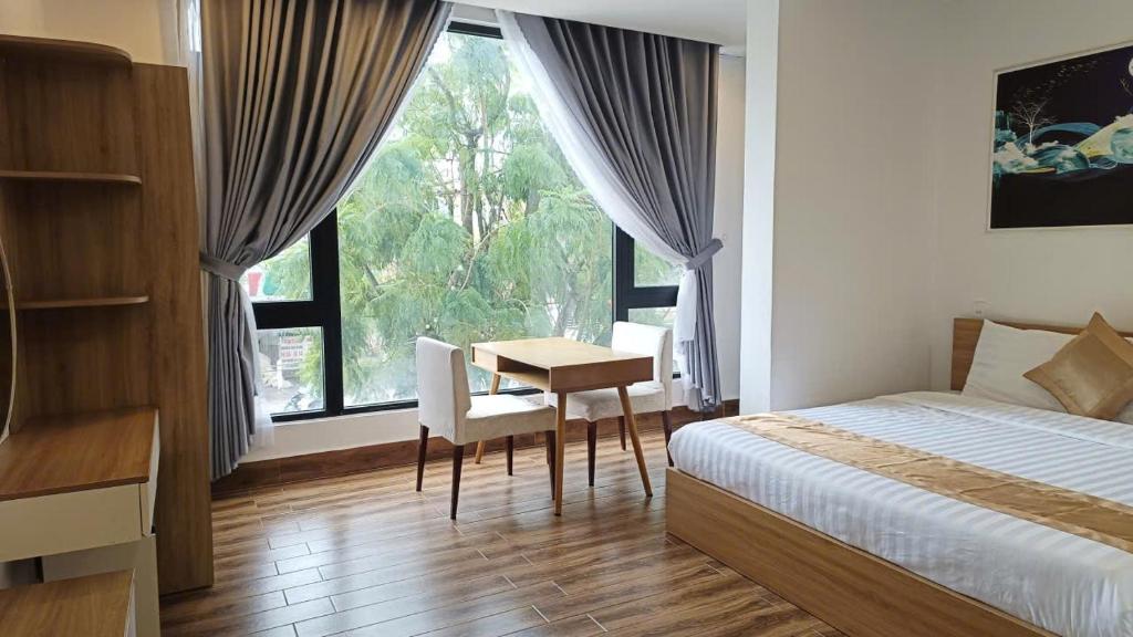 a bedroom with a bed and a table and a window at ROMANCE HOTEL DALAT in Da Lat