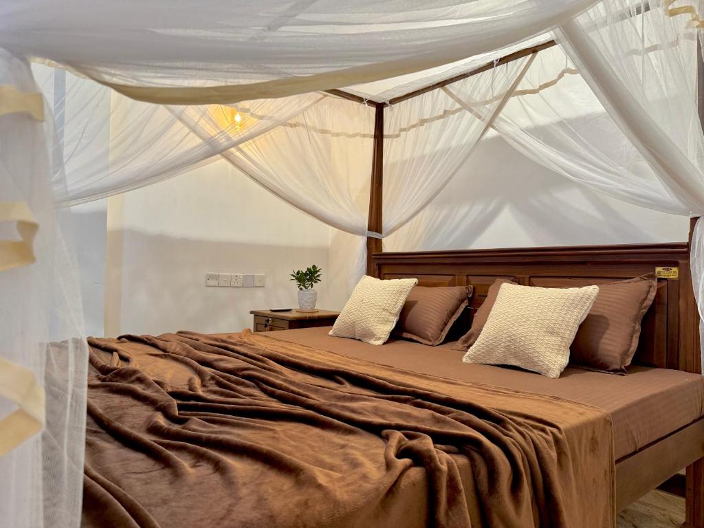 a bedroom with a large bed with a canopy at Sasmika Villa Surf and Yoga Hostel in Weligama