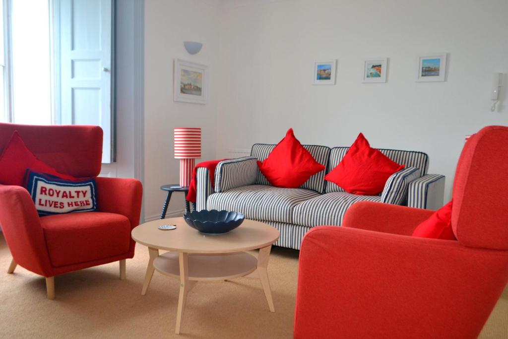 a living room with red chairs and a couch and a table at Manor House Apartment 2 in Shaldon