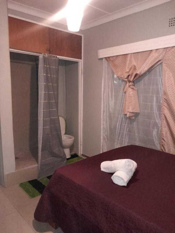 a bedroom with a bed and a bathroom with a toilet at Uptown Inn GuestHouse in Parys