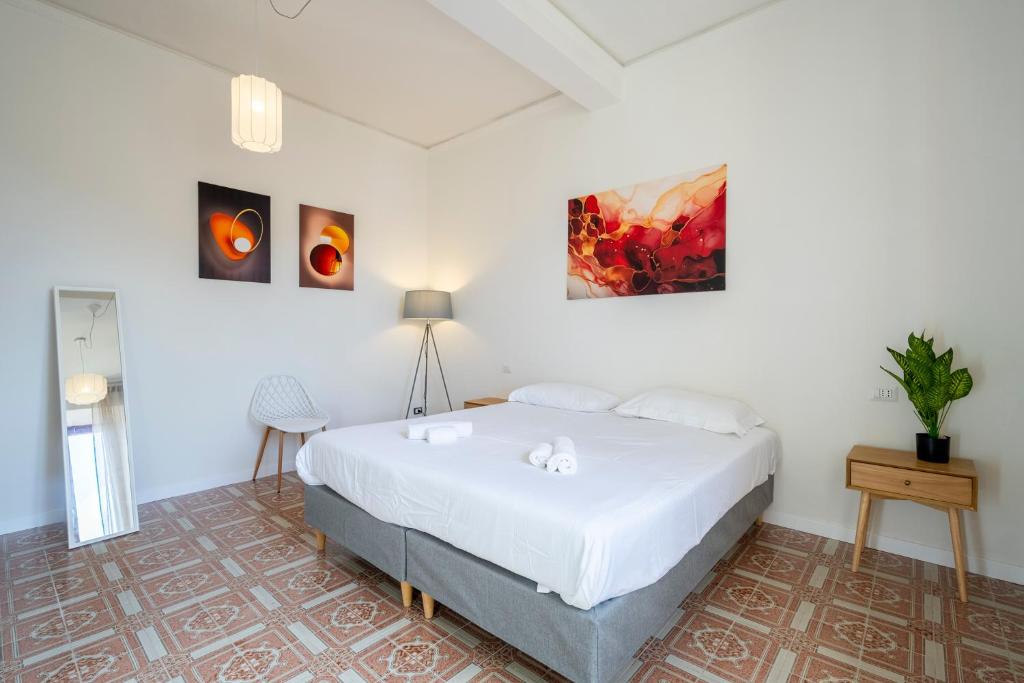 a bedroom with a white bed and paintings on the wall at Firenze Center - 9' to Duomo & Uffizi - AC, Wifi in Florence