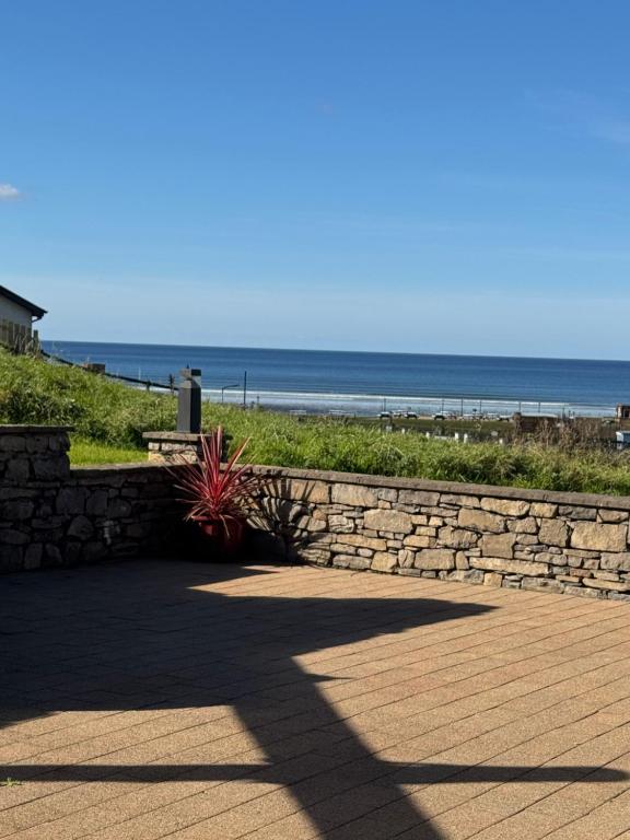 a stone wall next to a beach with the ocean at Beachhaven Rossnowlagh in Rossnowlagh
