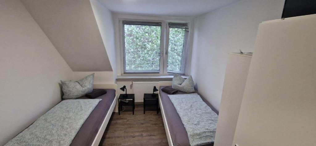 two beds in a small room with a window at Appartment Haus Rothenhaus Hamburg in Hamburg