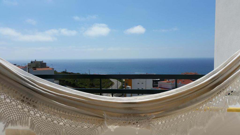 een hangmat op een balkon met uitzicht op de oceaan bij Casa da Gó in Ericeira