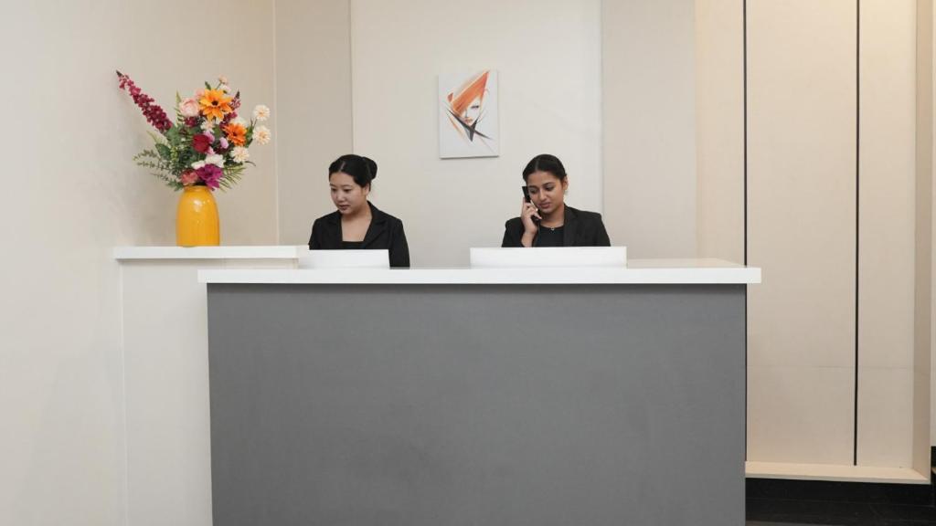 two women sitting at a counter talking on a cell phone at Ello Hotels in Bengaluru