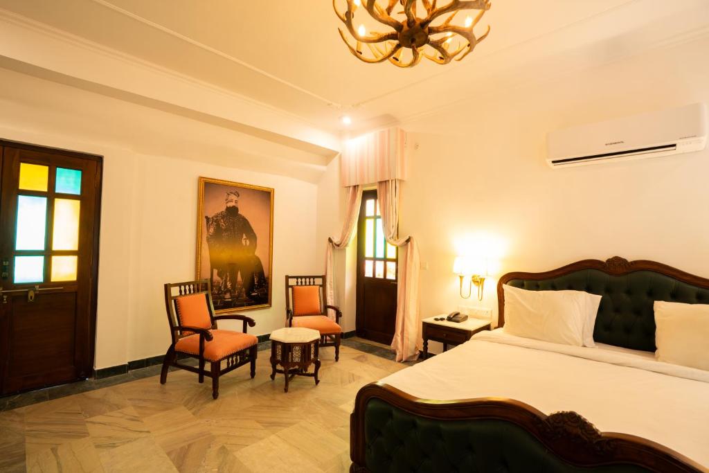 a bedroom with a bed and chairs and a chandelier at Medieval Forts & Palaces in Pachār