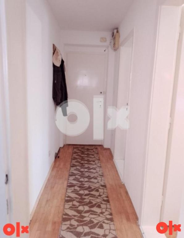 Un pequeño pasillo con una habitación de paredes blancas y una alfombra. en Apartman Čeliković, en Bosanski Šamac