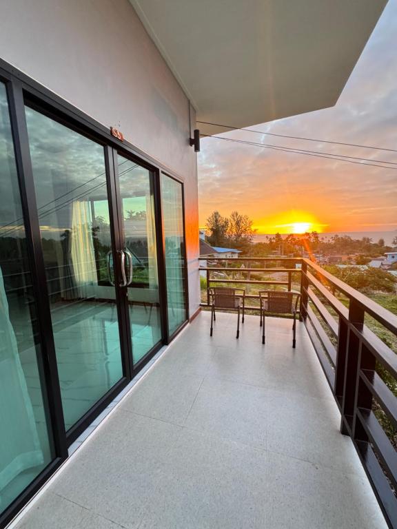 a balcony with chairs and a sunset in the background at Seaview phuwamin in Ko Lanta