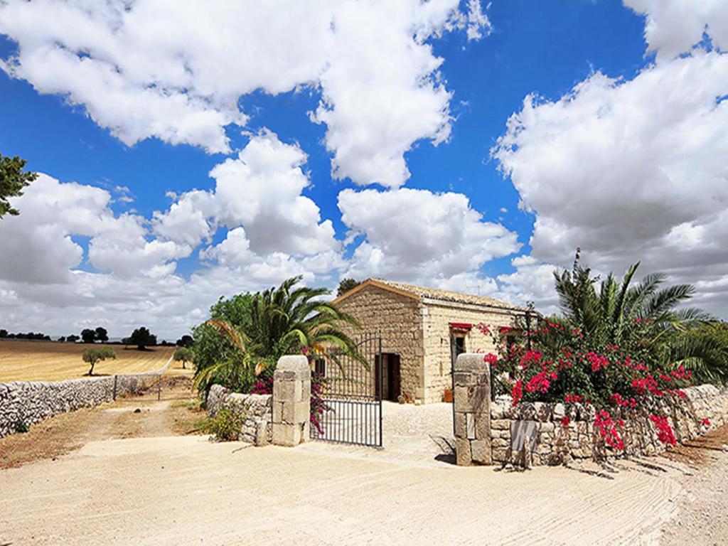 ein Gebäude mit einem Tor und Blumen davor in der Unterkunft Agriturismo Il Melograno in Cannizzara