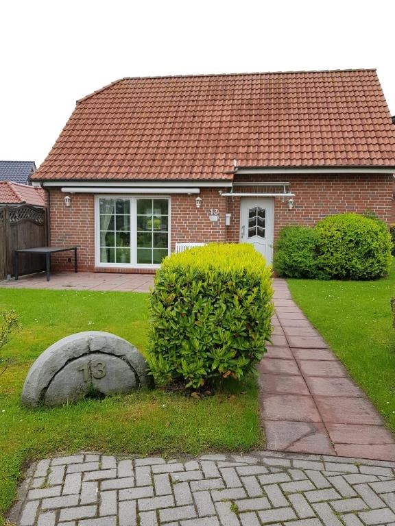 a brick house with a bush in the yard at Haus Kiki in Dornumersiel