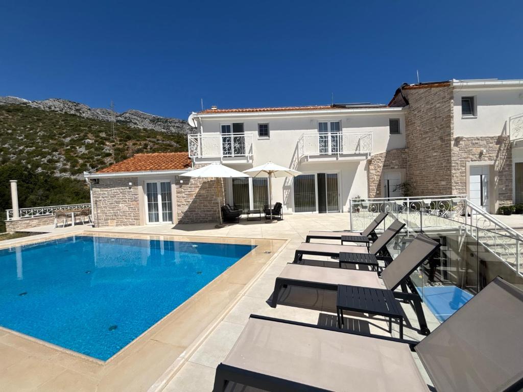 a villa with a swimming pool and lounge chairs at Orebic Luxury Villa Leopold in Orebić