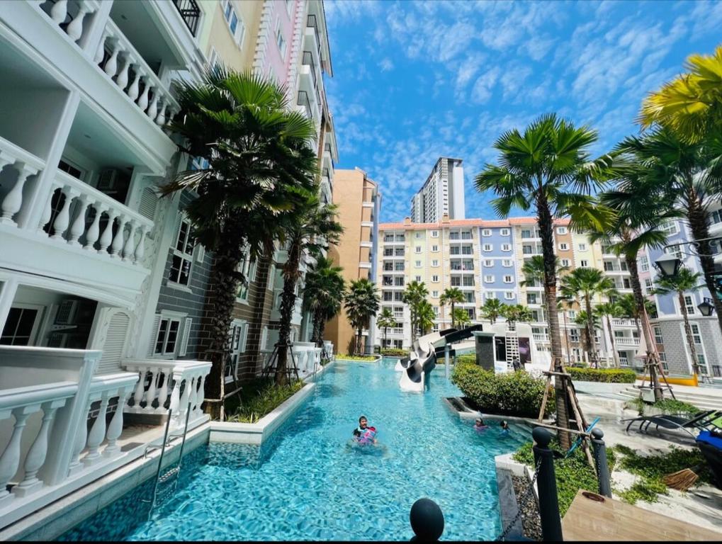 a pool in the middle of a city with palm trees at Seven seas cote Apartment in Na Jomtien