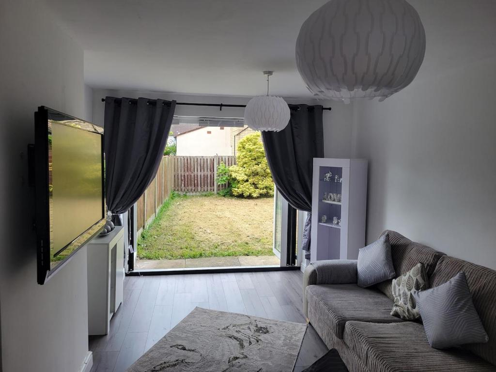 een woonkamer met een bank en een groot raam bij Comfy Home in Kirkby