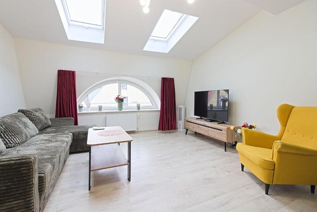 Una sala de estar con un sofá y un televisor. en Apartament Verona, en Elbląg
